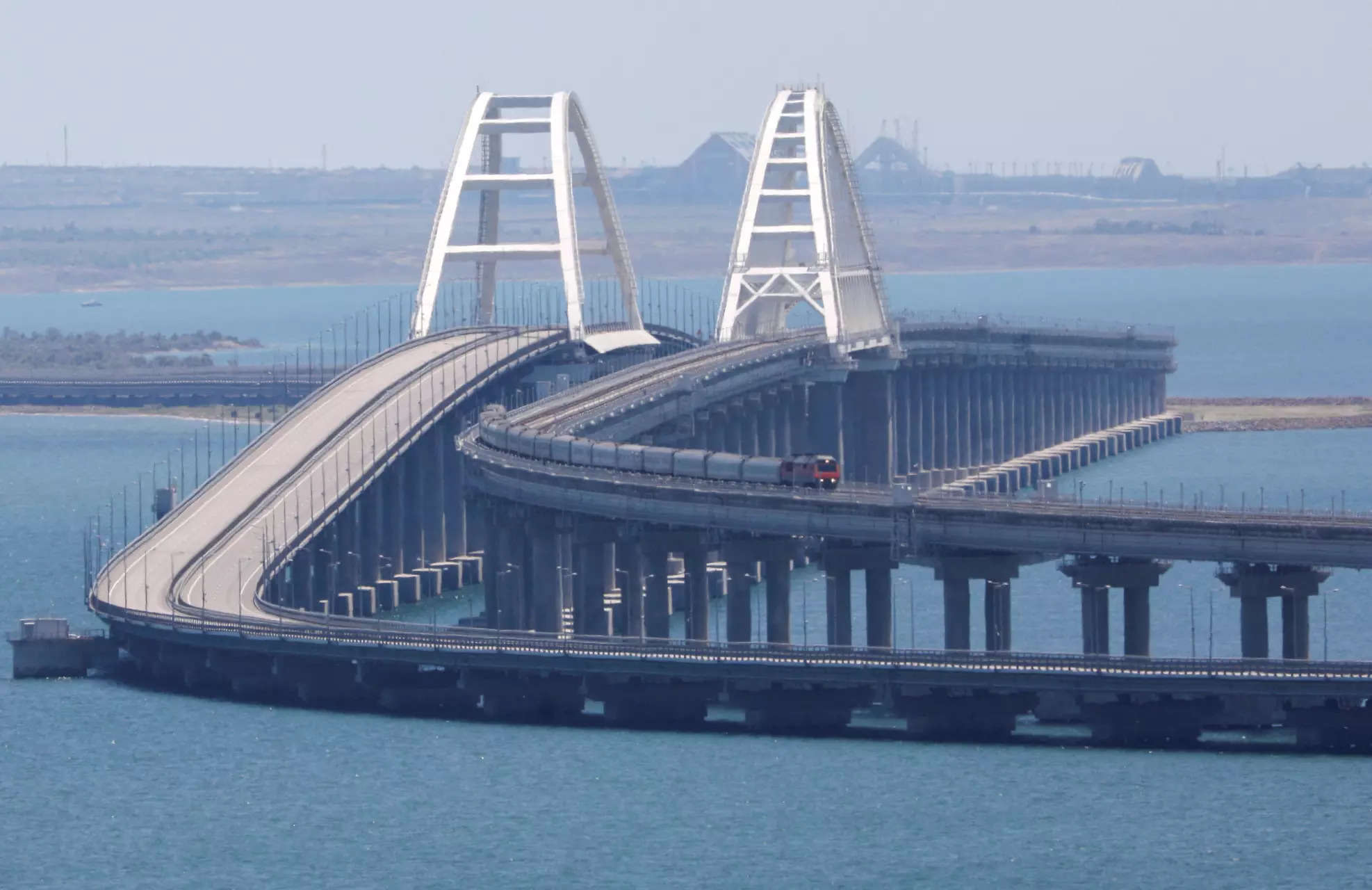 <p>A train moves along the Crimean Bridge, a section of which was damaged by an alleged overnight attack, as seen from the city of Kerch, Crimea, July 17, 2023. REUTERS/Alexey Pavlishak</p>