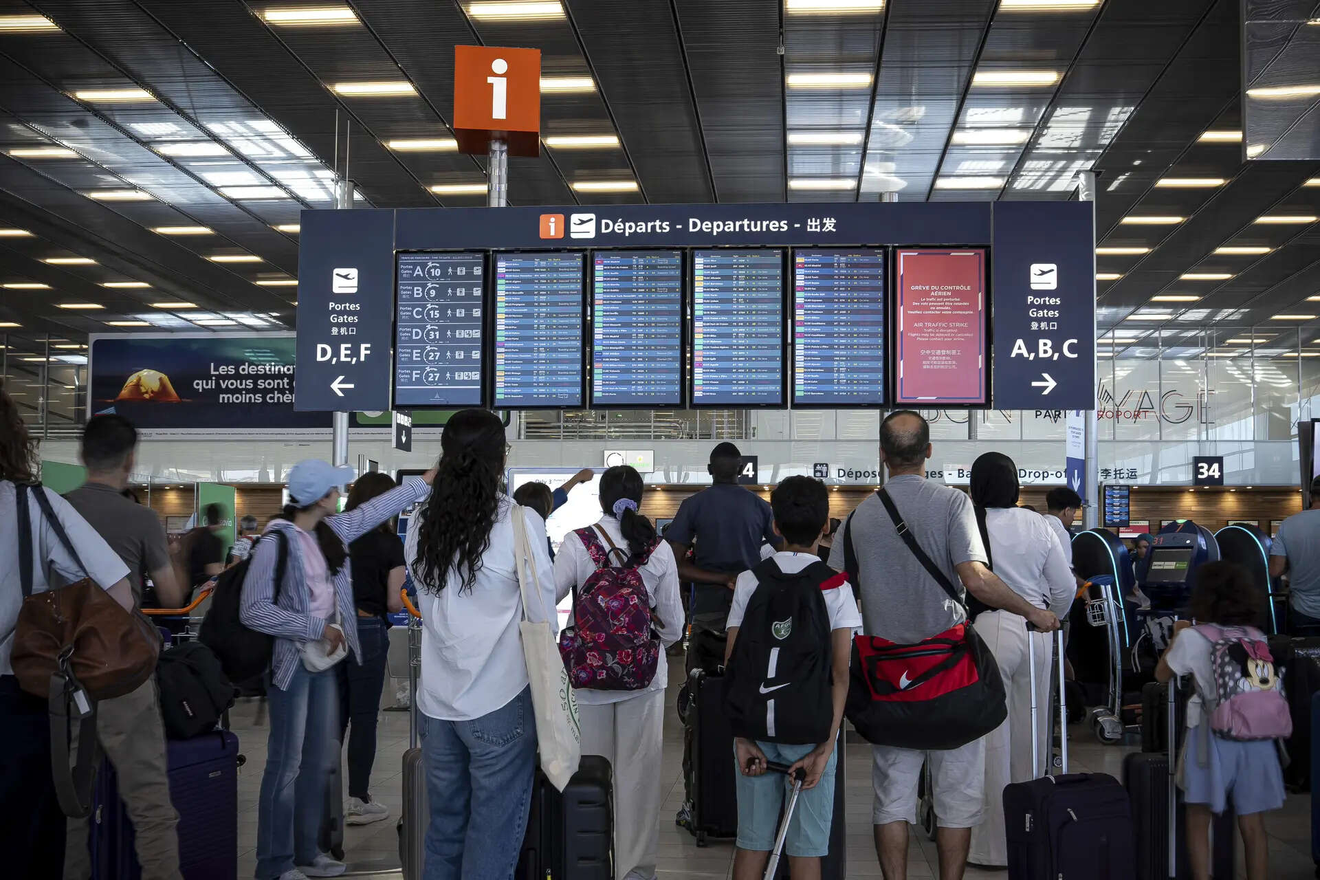 <p>Passengers look a departures information board at Orly airport, near Paris, as French air traffic controllers launched a two-day strike to demand better working conditions, </p>