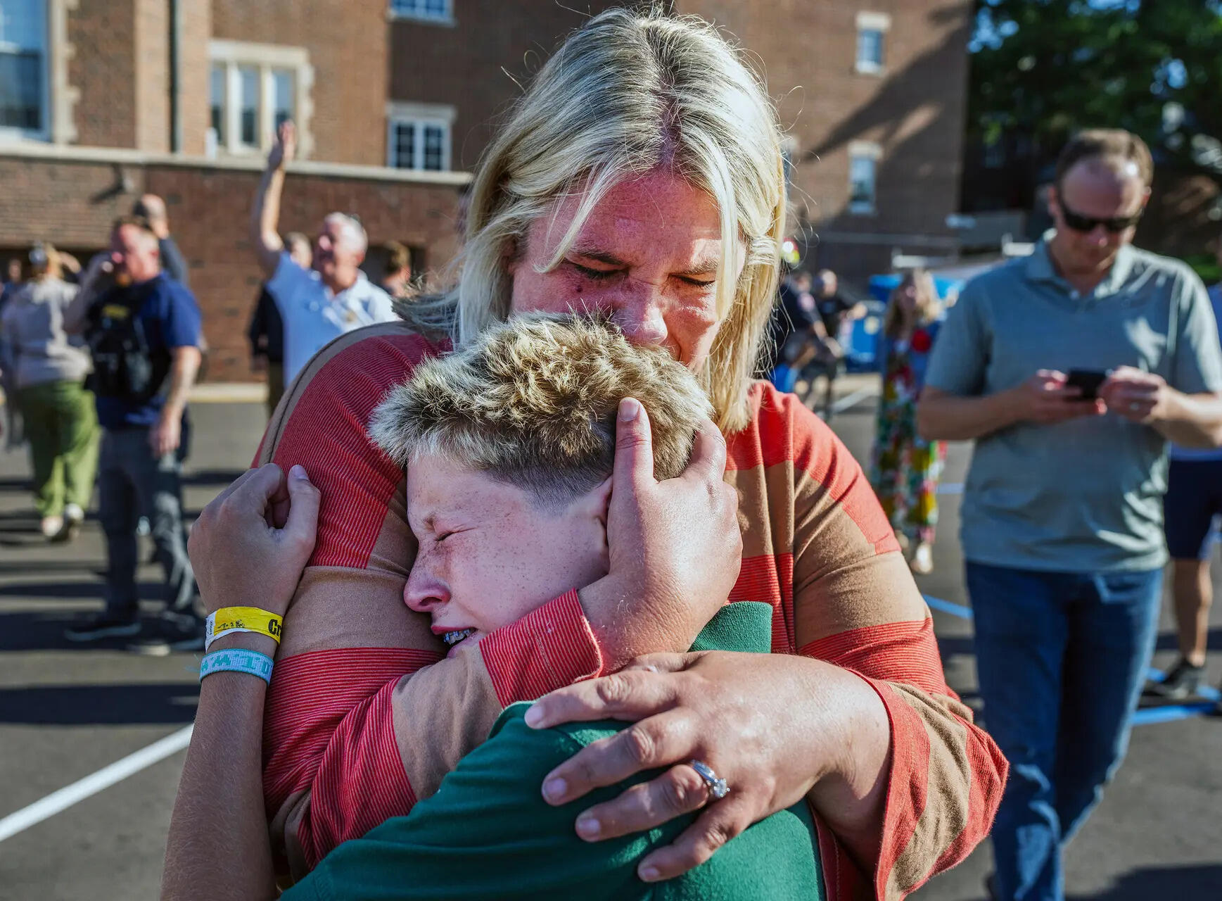 <p>Children in dark green uniforms trickled out of the school with adults, giving lingering hugs and wiping away tears</p>