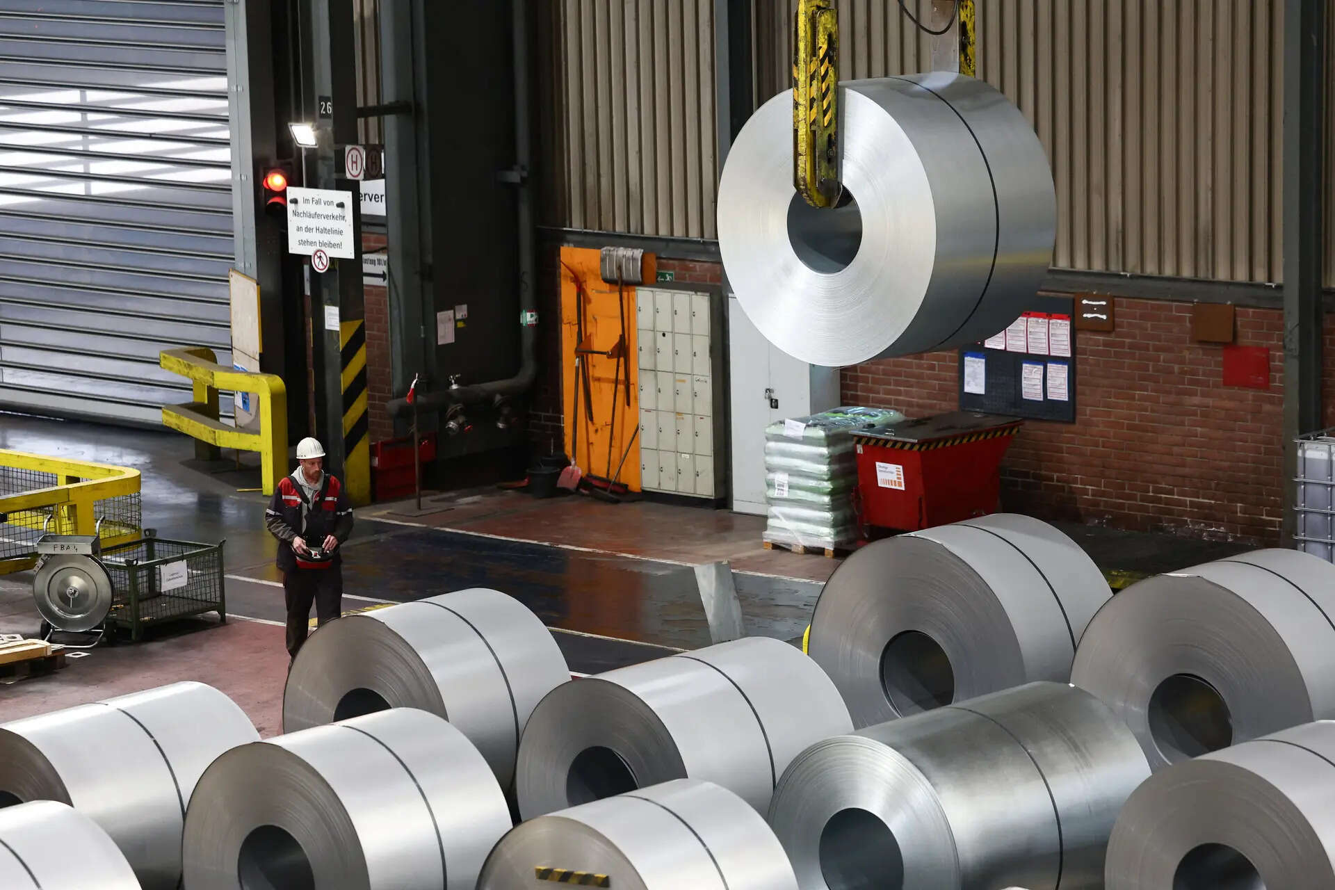 A worker moves a steel coil with a crane at a steel factory