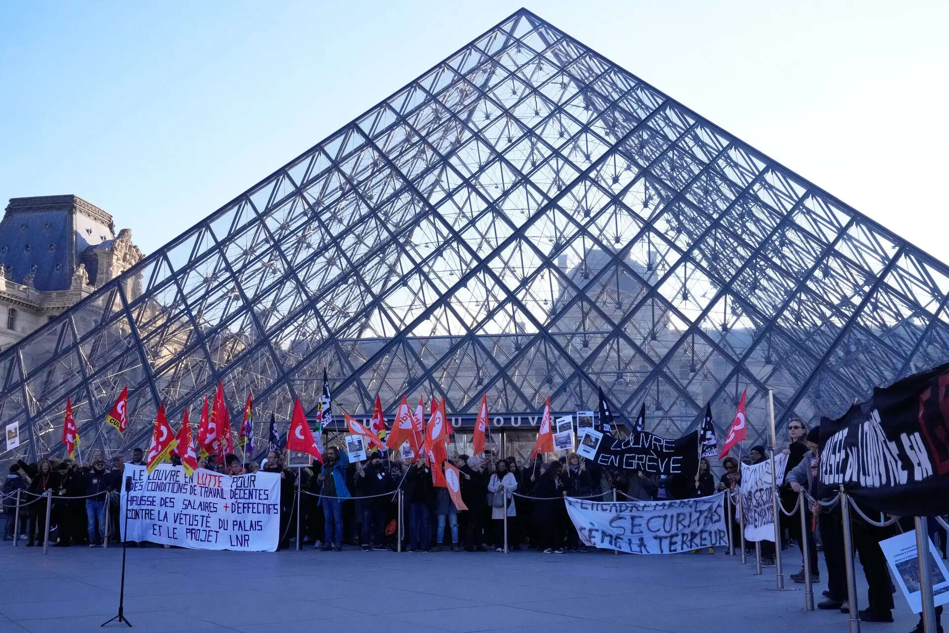 Workers display banners outside the Louvre museum after they voted to strike for the day over working conditions and other complaints, Monday, Dec. 15, 2025 in Paris. (AP Photo/Michel Euler)