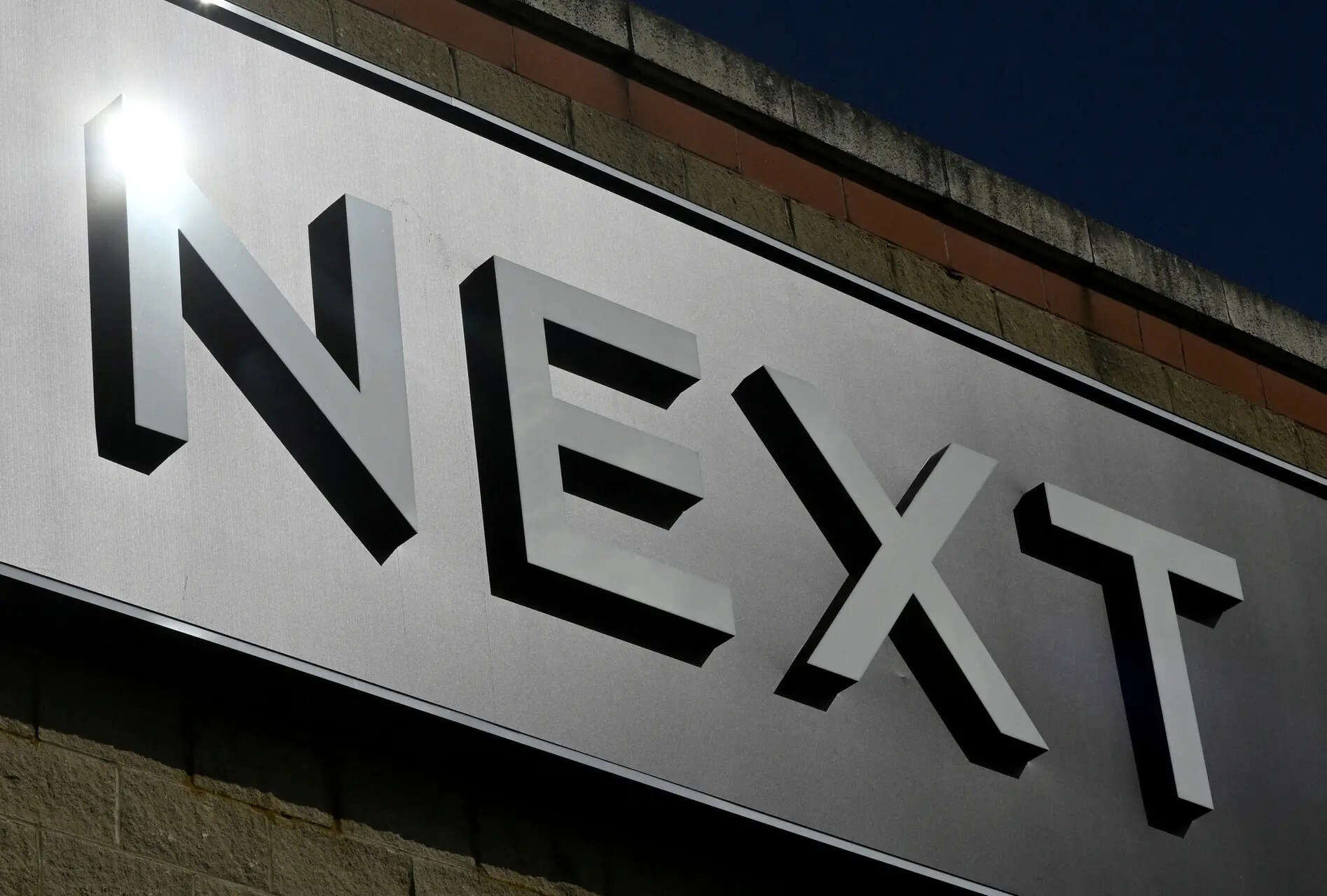 FILE PHOTO: Signage on the exterior of a Next clothing retail store is seen in London, Britain, March 25, 2023. REUTERS/Toby Melville/File Photo