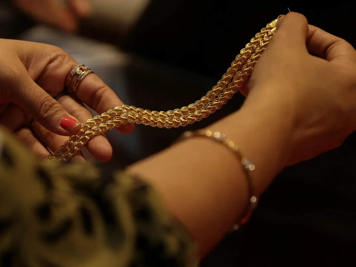 A customer holds a gold chain at a jewellery store in Mumbai, India