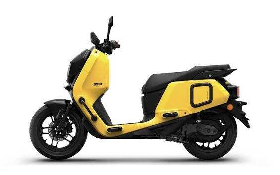 A lineup of colorful motor scooters parked outdoors at a service area, showcasing modern design.
