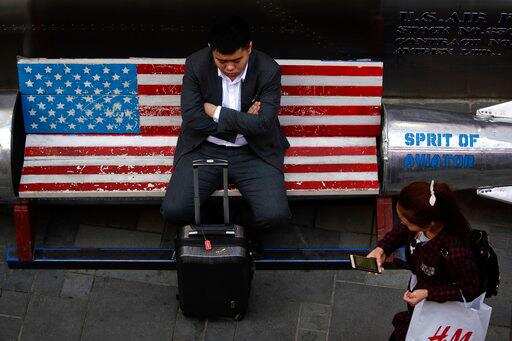 A woman walks by a man sitting outside an American apparel store at a shopping mall in Beijing, Tuesday, April 10, 2018. China's President Xi Jinping promised to cut auto import taxes, open China's markets further and improve conditions for foreign companies in a speech Tuesday that called for international cooperation against a backdrop of a spiraling dispute with Washington over trade and technology.Photo/Andy Wong)
