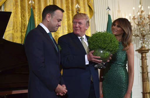 President Donald Trump, center, smiles as he is presented with a traditional gift of a bowl of shamrocks from Irish Prime Minister Leo Varadkar, left, during a St. Patrick's Day reception in the East Room of the White House in Washington, Thursday, March 15, 2018. First lady Melania Trump stands at right.Photo/Susan Walsh)