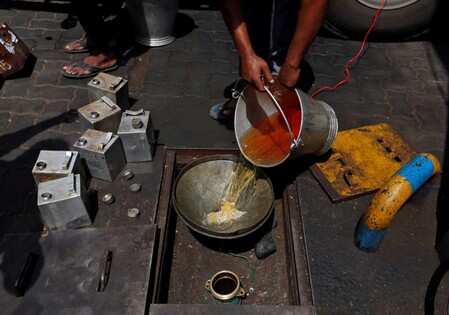 A man pours petrol into an underground tank at a fuel station.