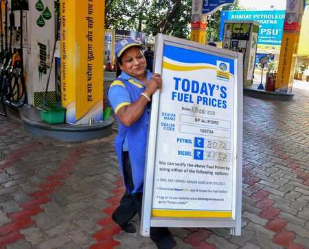 An employee carries a notice board with fuel prices display on it, at an all-women fuel station, in Kolkata.