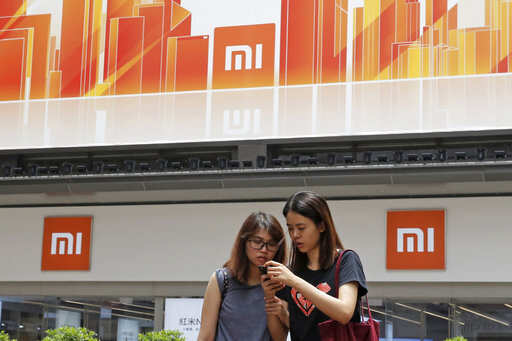 In this Wednesday, June 20, 2018, photo, people use their smartphone outside a Xiaomi store in Hong Kong. Xiaomi, a Chinese startup that helped to pioneer the trend toward ultra-low-priced smartphones, is preparing for what would be the biggest initial public offering since e-commerce giant Alibaba's in 2014. The 8-year-old is a star among the Chinese unicorns, a term that refers to startup companies that are valued at more than $1 billion. It has a dedicated Chinese fan base and its media-savvy leader is an Asian celebrity. But it is untested outside the region.Photo/Kin Cheung)