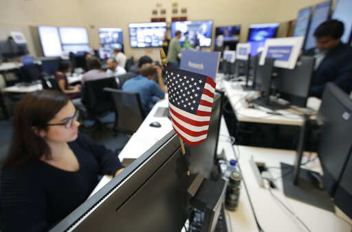 A flag of the United State is shown between monitors as workers sit at their desks during a demonstration in the war room, where Facebook monitors election related content on the platform, in Menlo Park, Calif., Wednesday, Oct. 17, 2018.Photo/Jeff Chiu)