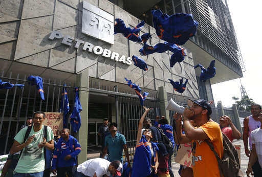 FILE - In this Feb. 4, 2015 file photo, workers whose company is contracted by Brazil's state oil company Petrobras throw their work uniforms at the company's building headquarters to protest corruption, in Rio de Janeiro, Brazil. Brazil's President-elect Jair Bolsonaro on Monday, Nov. 19, 218, named Roberto Castello Branco, a pro-market reformer, as future chief executive of the country's state-controlled oil company, Petrobras. Castello Branco, a former member of Petrobras' board, has advocated privatizing the oil giant.Photo/Silvia Izquierdo, File)
