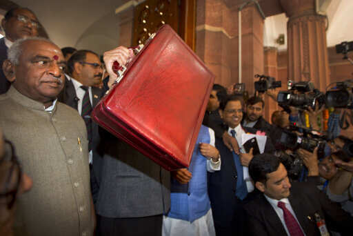 Junior Finance minster Pon Radhakrishnan, left, looks as interim Finance Minister Piyush Goyal, center, shows a briefcase containing budget documents at parliament house. Photo/Manish Swarup)