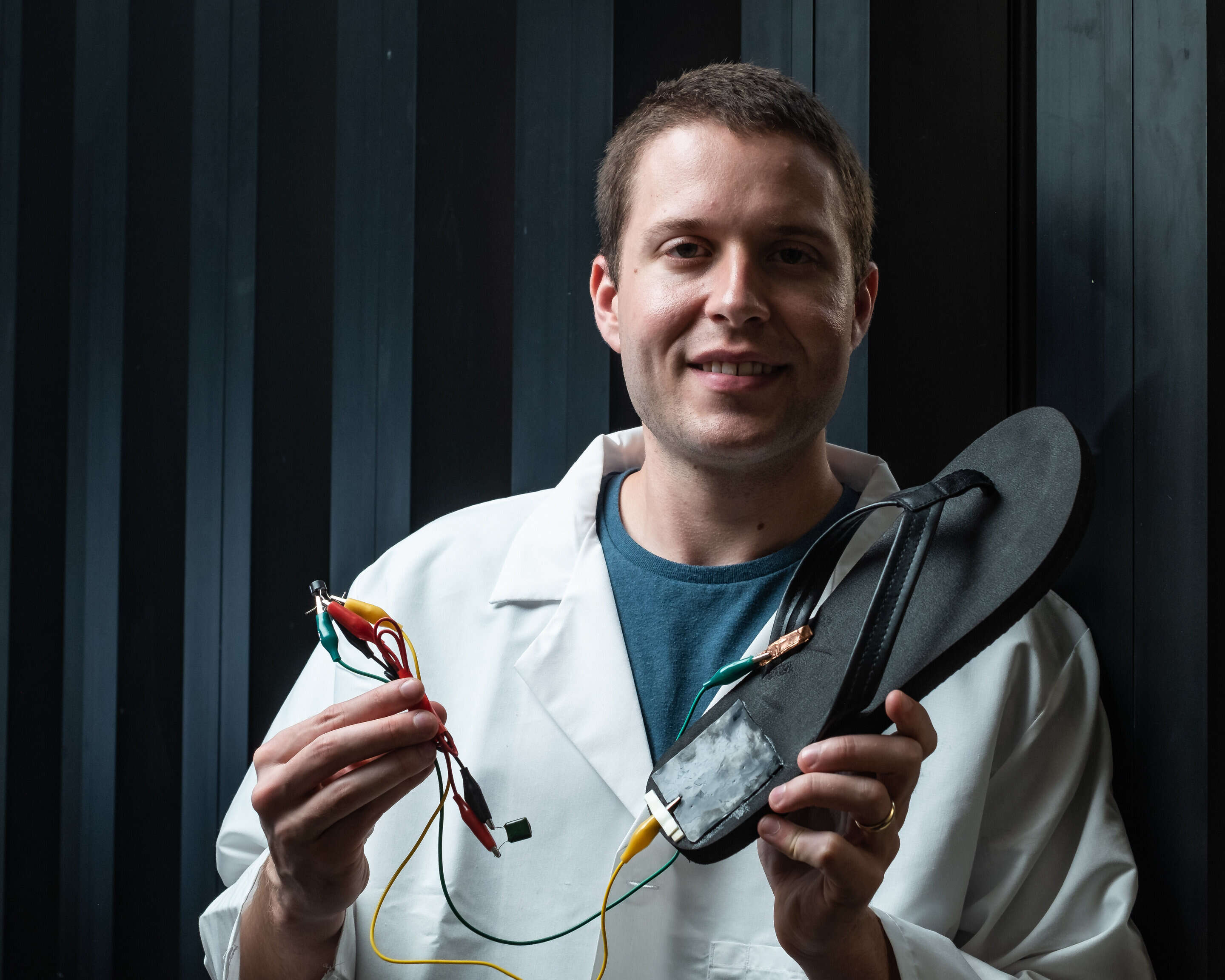 Rice University postdoctoral researcher Michael Stanford holds a flip-flop with a triboelectric nanogenerator, based on laser-induced graphene, attached to the heel