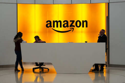 FILE - In this Feb. 14, 2019, file photo people stand in the lobby for Amazon offices in New York. Amazon is closing its U.S. restaurant delivery service, a 4-year-old business that failed to take off amid fierce competition from Uber Eats, Door Dash and others. The service, called Amazon Restaurants, offered delivery in more than 20 cities in the U.S. It was expanded into the United Kingdom, but Amazon shut it down late last year.Photo/Mark Lennihan, File)