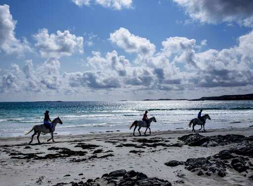 People ride horses along the beach at the Atlantic Ocean in Ballyconneely, Ireland, Wednesday, July 17, 2019.Photo/Michael Probst)