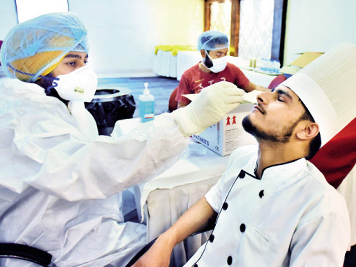 A health worker collects a nasal swab sample of an employee of Shivalik View Hotel on Sunday