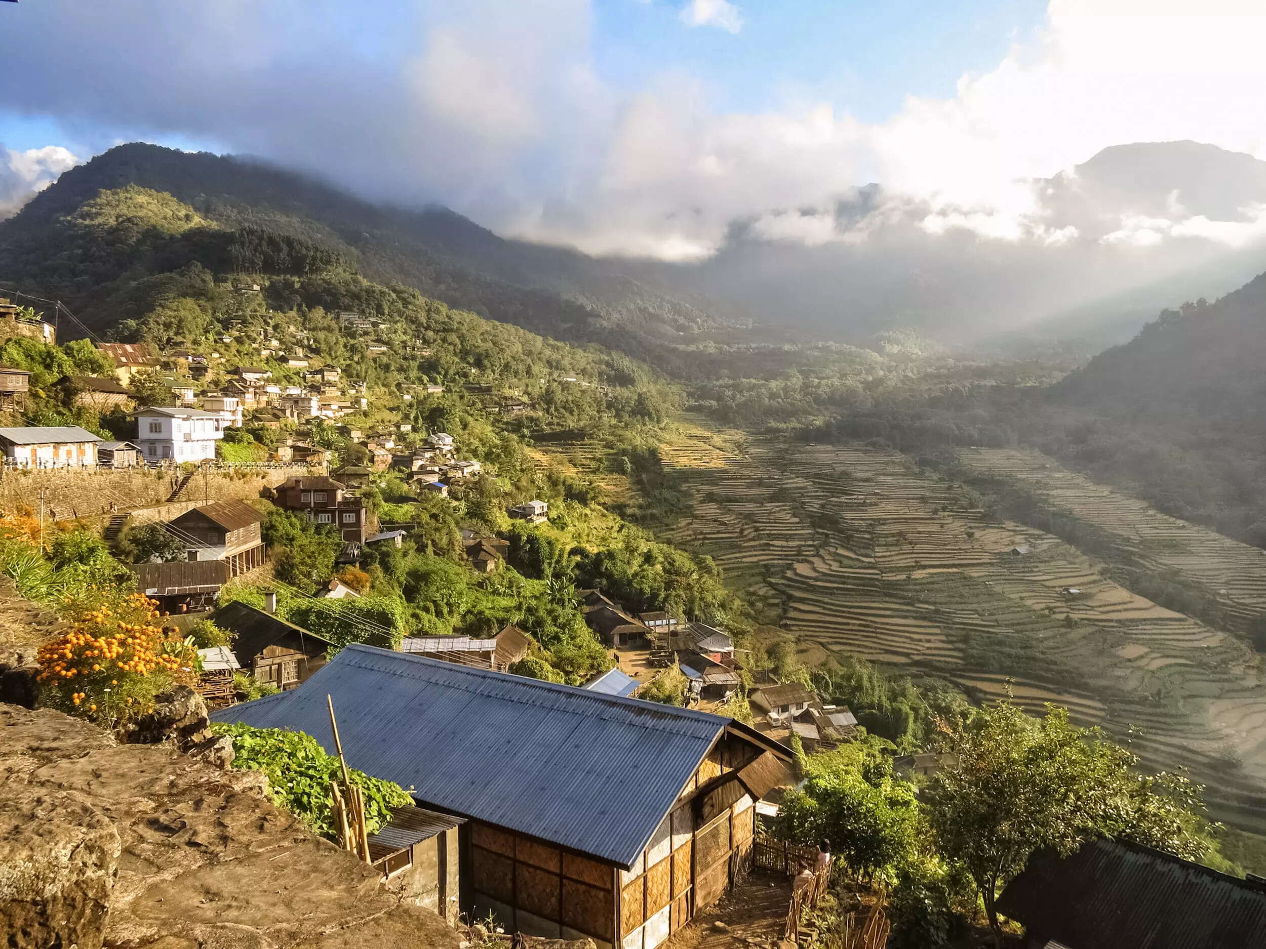 A picturesque village nestled in the hills of Rural Tourism North, showcasing traditional houses and stunning terraced fields under a misty sky.