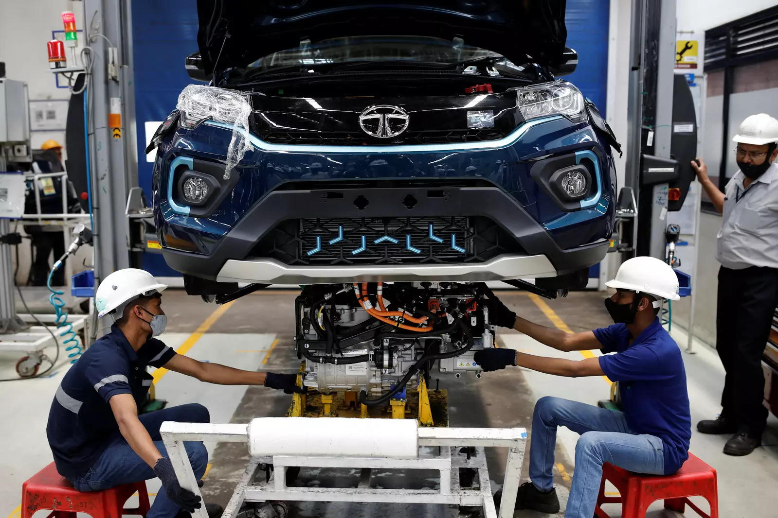  Workers install the electric motor inside a Tata Nexon electric sport utility vehicle (SUV) at the Tata Motors plant in Pune, India, April 7, 2022. (Source: Reuters)