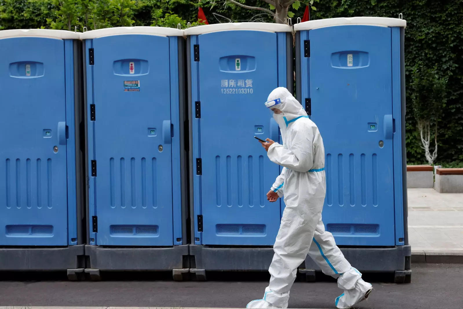 A worker in a protective suit walks past mobile toilets near an area under lockdown, amid the coronavirus disease (COVID-19) outbreak in Beijing, China May 12, 2022. REUTERS/Carlos Garcia Rawlins