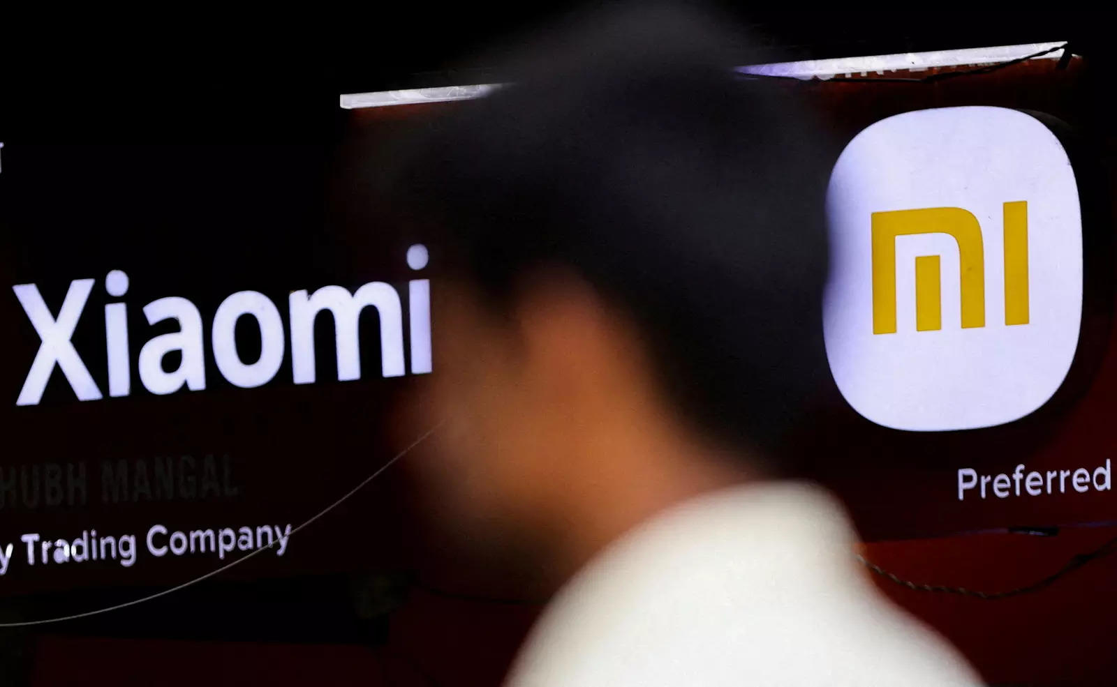     FOTO FILE: Seorang pria berjalan melewati logo Xiaomi, pembuat elektronik konsumen Cina, di luar sebuah toko di Mumbai, India 11 Mei 2022. REUTERS/Francis Mascarenhas