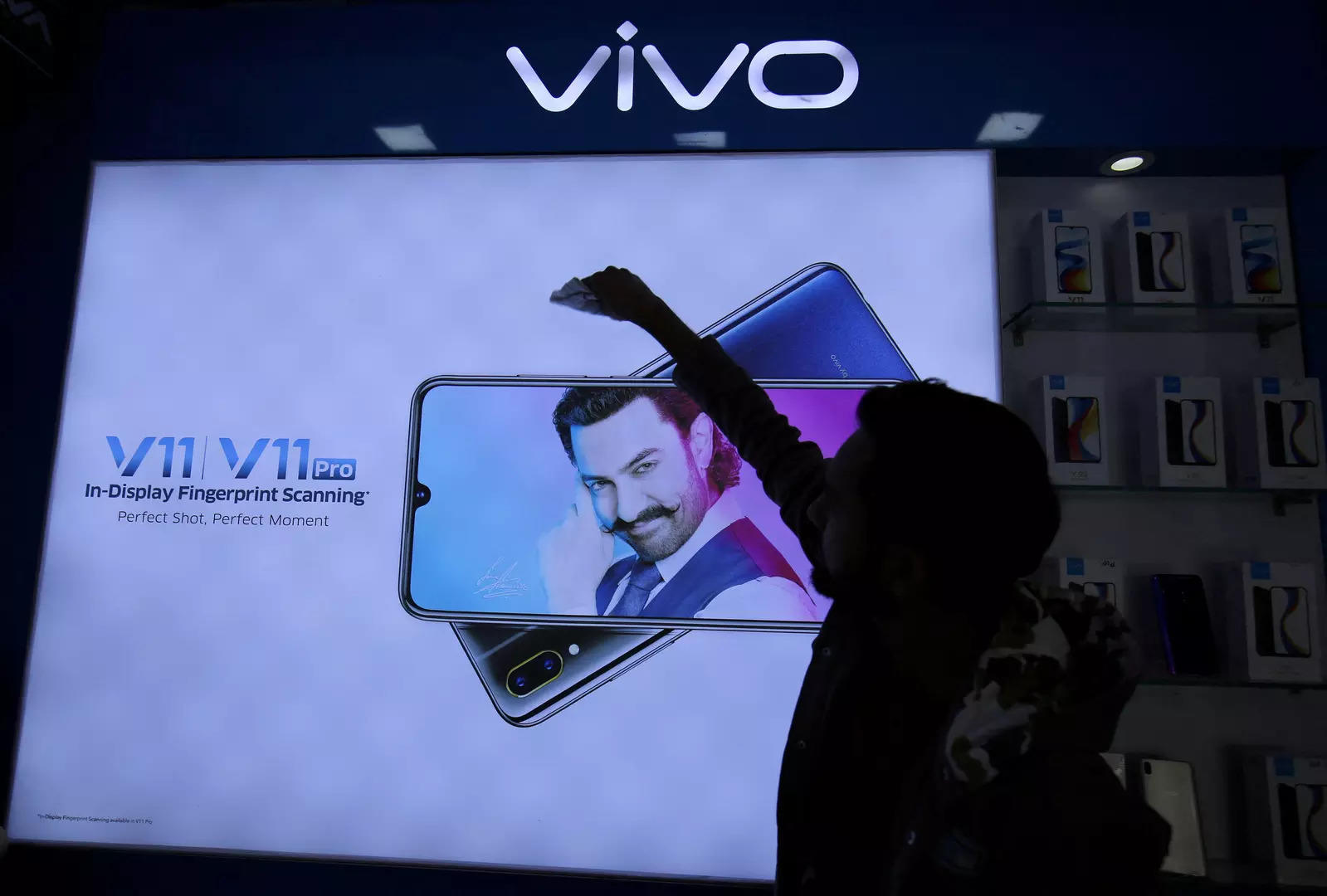     BESTANDSFOTO: Een man maakt een scherm schoon met daarop een telefoonmodel van het Chinese smartphonebedrijf Vivo in een winkel in Ahmedabad, India, 14 december 2018.