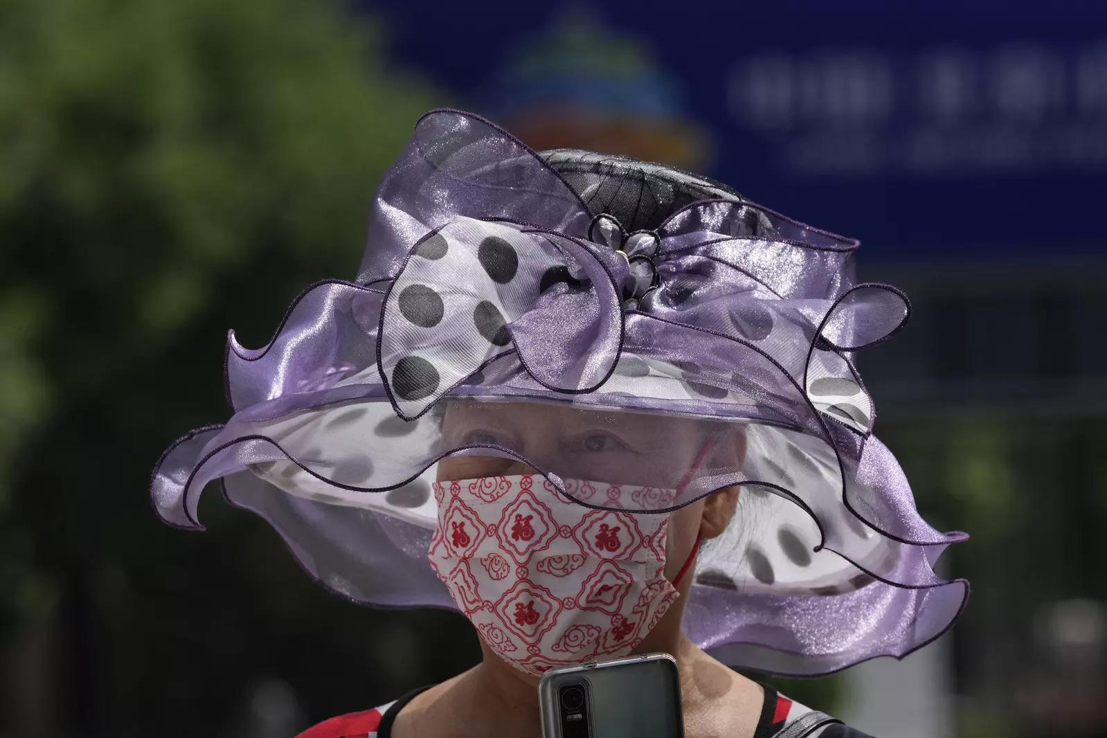  A woman wearing a mask and a colorful hat walks on the street, Thursday, July 7, 2022, in Beijing. (AP Photo/Ng Han Guan)