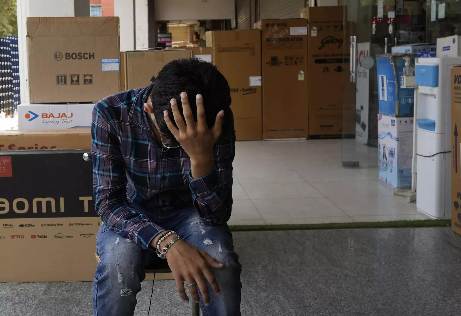   Sahil Rajput, 21, sits outside an electronic shop where he works in Rohtak, India, July 18, 2022. Rajput has been fervently preparing for a job in the army, working in a low-paid data-entry job to afford private coaching to become a soldier and support his unemployed parents.  But in June, the government overhauled military recruitment to cut costs and modernize, changing long-term postings into four-year contracts after which only 25% of recruits will be retained.  Rajput knows he might not be able to get a permanent army job.  "But I have no other options,"  he said.  (AP Photo/Manish Swarup)