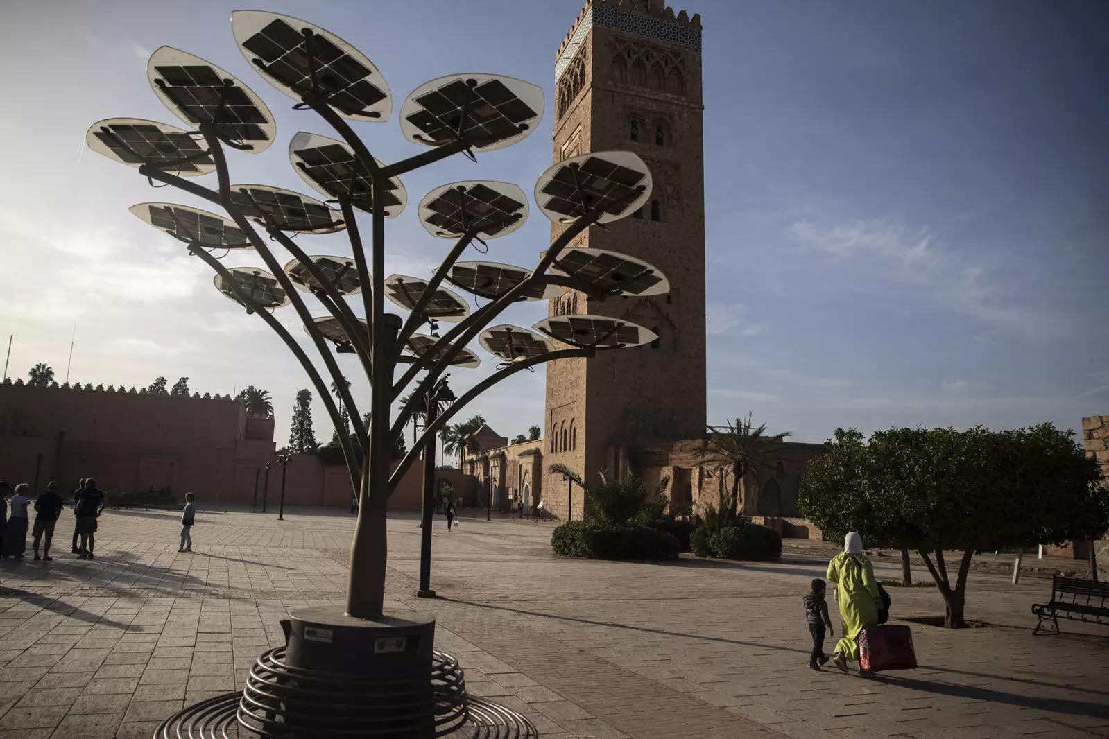  FILE - People walk past a solar tree that generates energy using panels, in front of the landmark Kotoubia mosque in Marrakech, Morocco, Nov. 12, 2022. The majority of developing nations are set to miss out on the economic benefits of booming green technologies, a United Nations report warned Thursday, March 16, 2023. The U.N.’s agency for trade and development, or UNCTAD, said that unless the international community and national governments actively tend to green tech industries in developing countries, the benefits associated with lower-emission technologies will be near inaccessible for many poorer nations, including many in Africa. (AP Photo/Mosa’ab Elshamy, File)