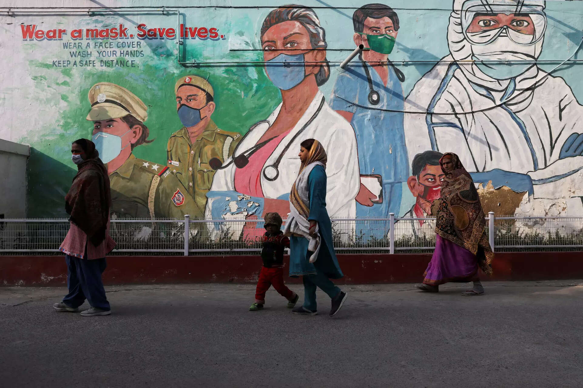  Women walk past a graffiti amidst the spread of the coronavirus disease (COVID-19) in New Delhi, India, February 7, 2022. REUTERS/Anushree Fadnavis